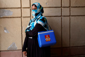 Vaccinator with kit box waits for her colleagues to do anti-polio campaign in a low-income neighbourhood in Karachi