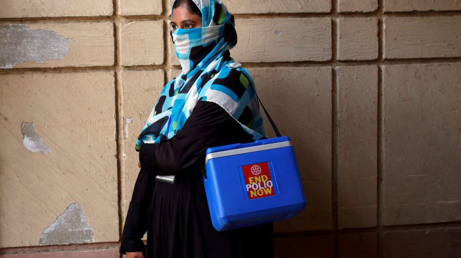 Vaccinator with kit box waits for her colleagues to do anti-polio campaign in a low-income neighbourhood in Karachi