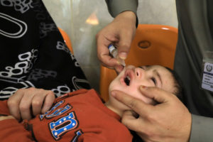 Boy receives polio vaccine drops by anti-polio vaccination workers at a booth outside a hospital in Peshawar